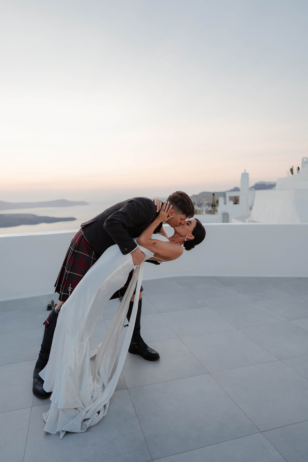 A romantic kiss after the wedding with the Santorini cliffs in the background