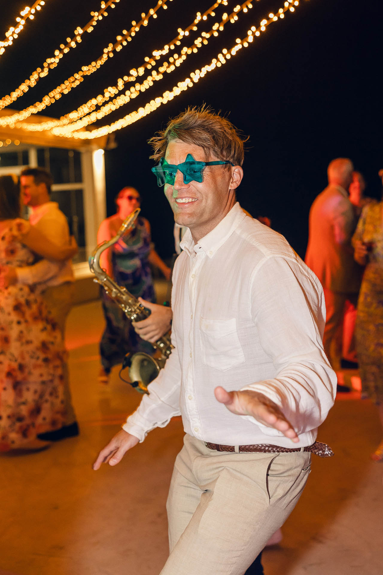 how to create wedding content - Wedding guest dancing with star-shaped glasses under string lights - Marvellous Wedding